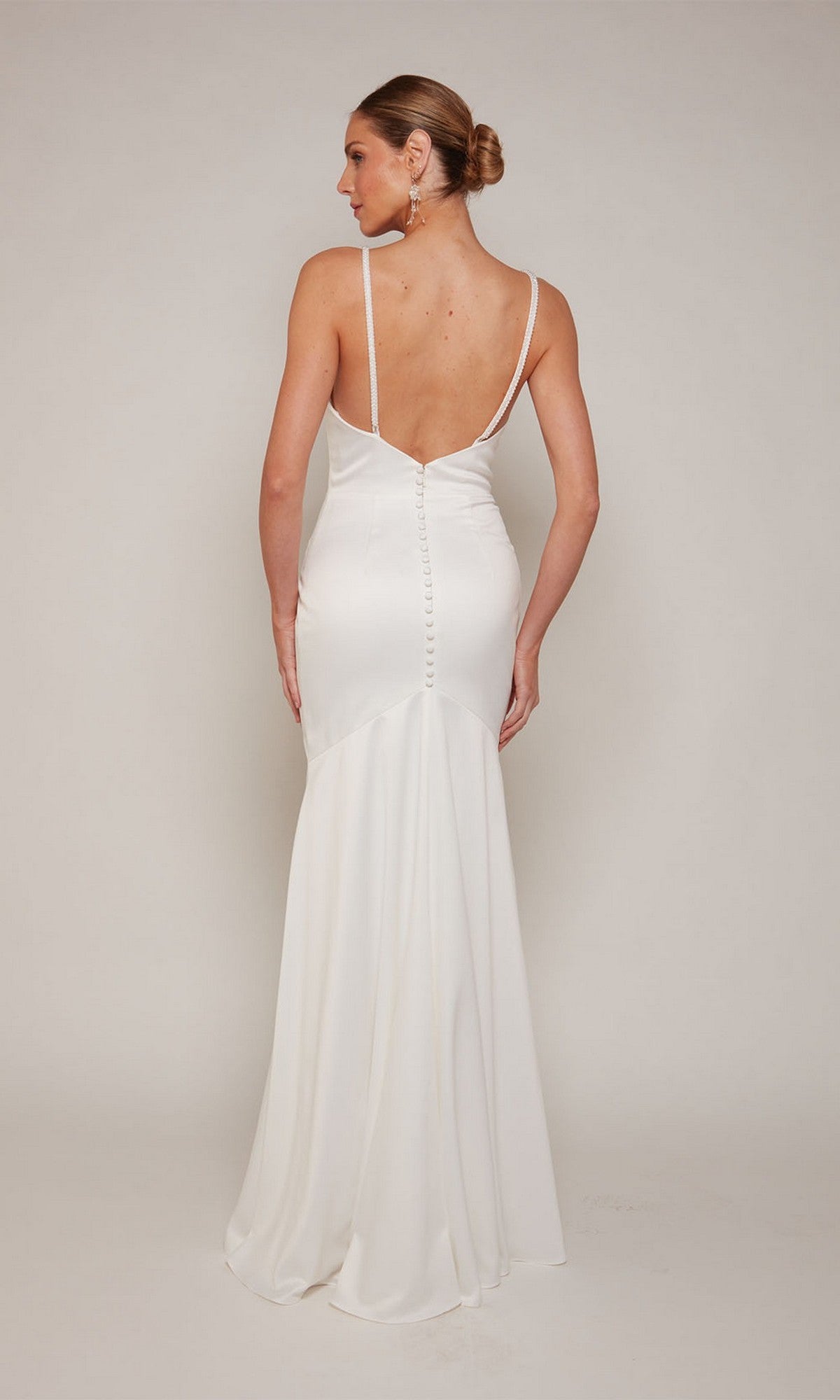 A woman wearing the Alyce 7090 long formal dress, featuring satin fabric, thin straps, and a low back, stands facing away from the camera against a plain background.